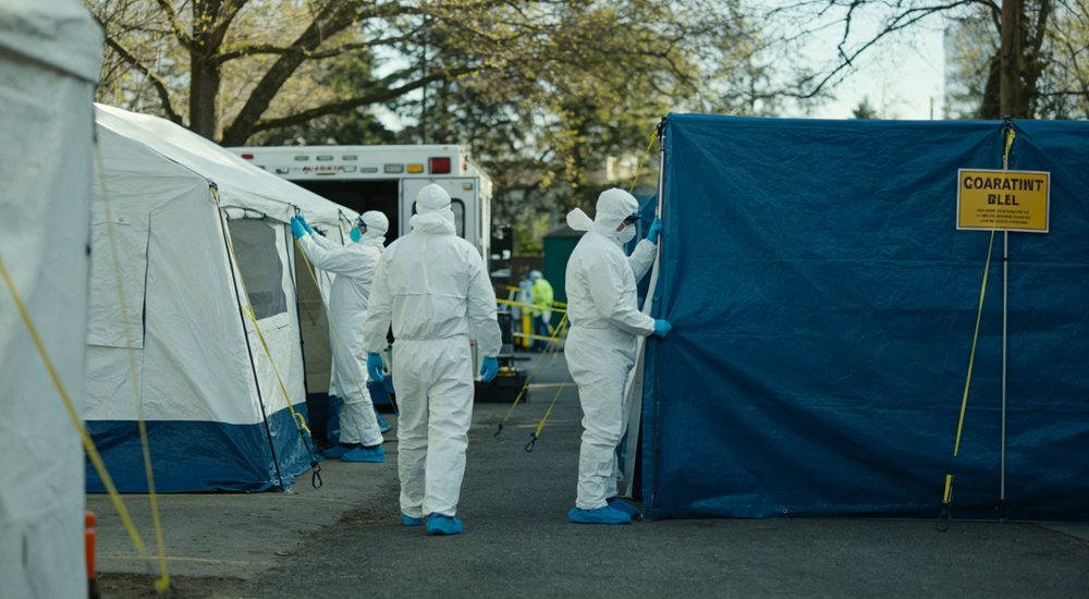 Disease control workers in medical coveralls setting up quarantine zone, emergency response
