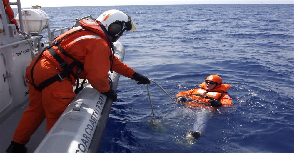 Wide view of coast guard rescue boat approaching vessel during maritime emergency showing professional rescue