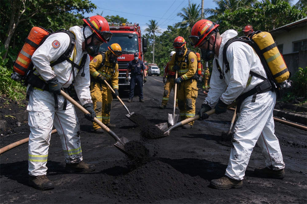 Rescue crew in PPE cleaning volcanic ash from roads, volcano emergency response and relief operations